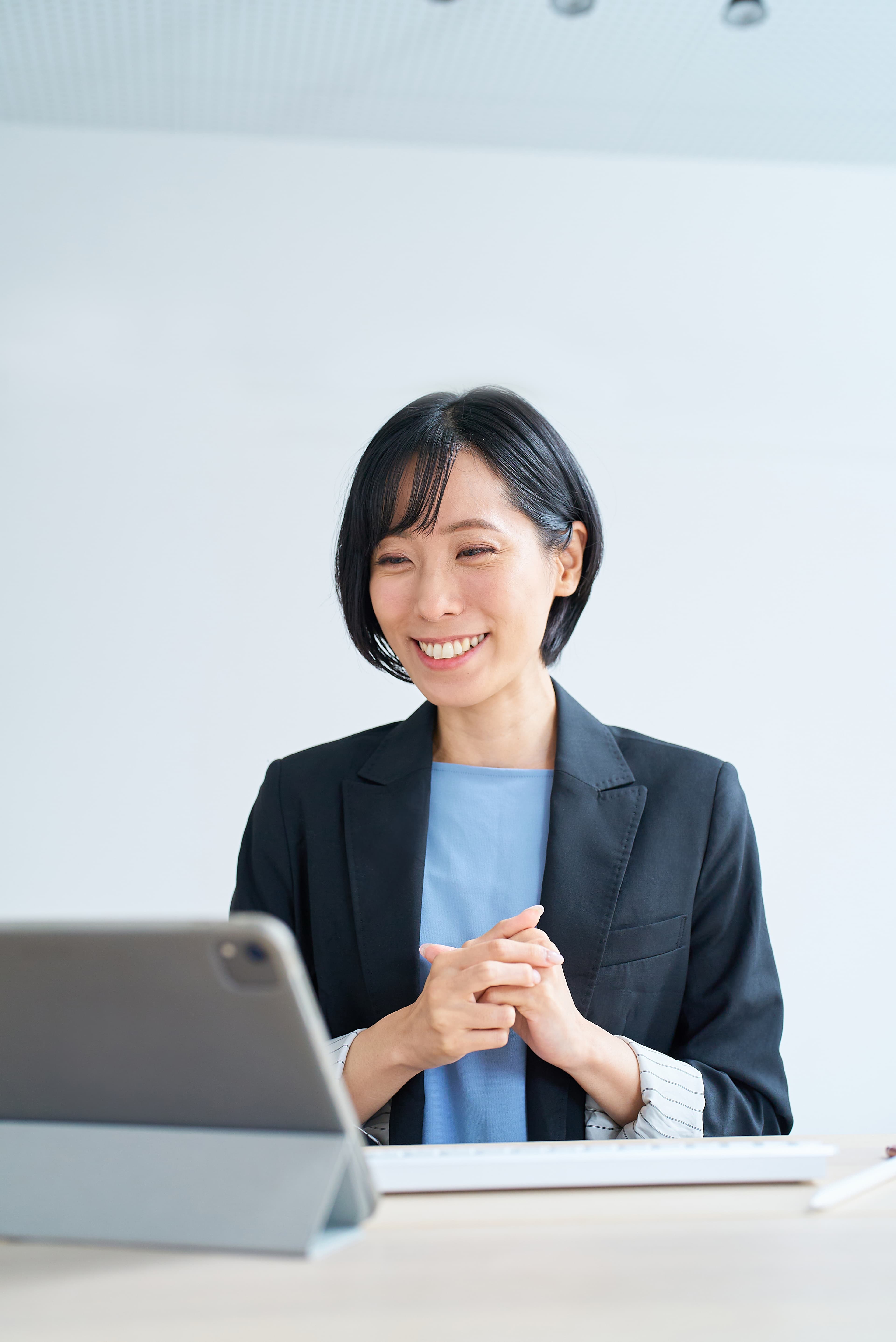 タブレットを前に、オンライン面談で笑顔で話す女性